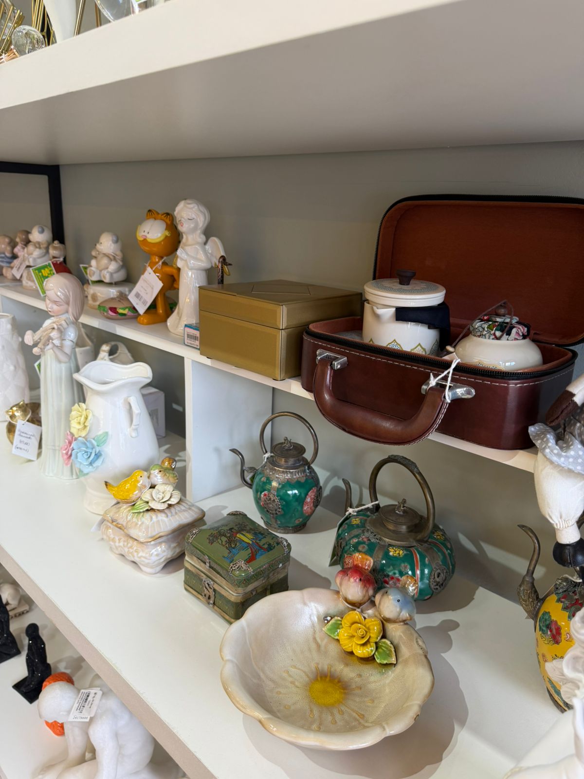 Prateleiras com bules, porcelanas e peças de coleção Essência Decor